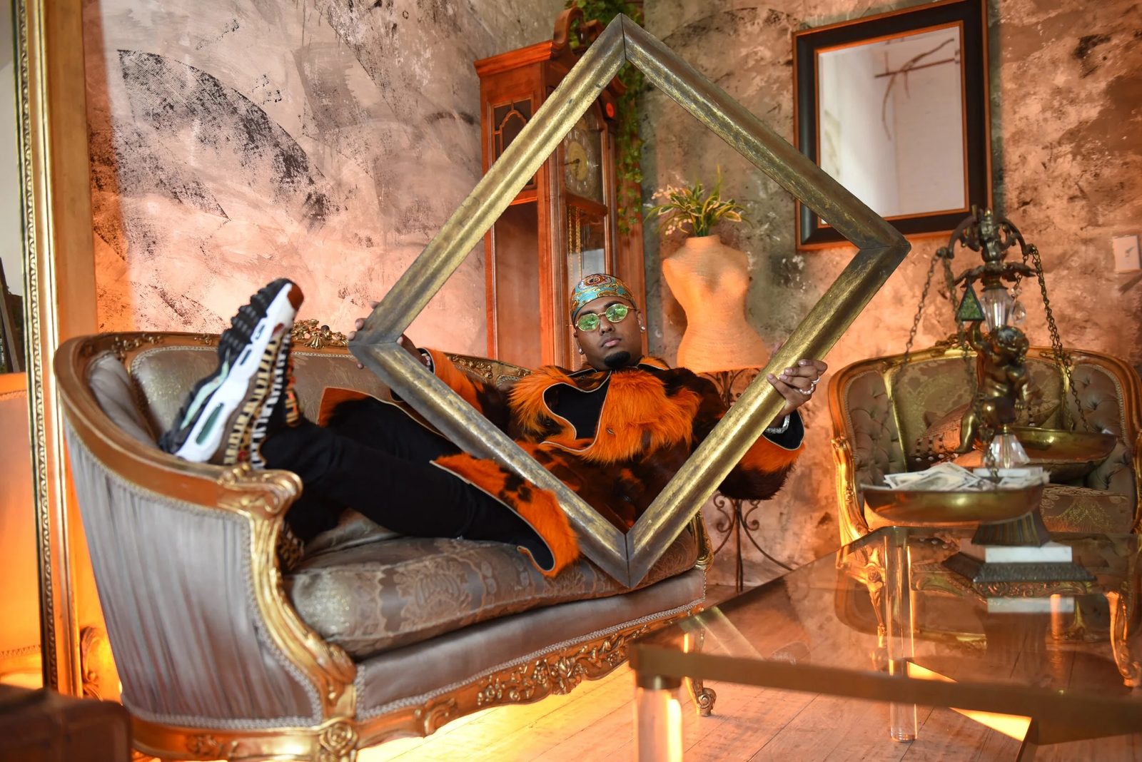 DJ SpinKing framed in gold on a vintage couch